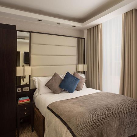 Montcalm Brewery Townhouse Hotel Лондон Екстериор снимка The image shows a cozy bedroom. It features a comfortable double bed with a light-colored duvet and decorative pillows in shades of blue and gray. The headboard is upholstered in a soft material, and there are bedside lamps on either side of the bed.