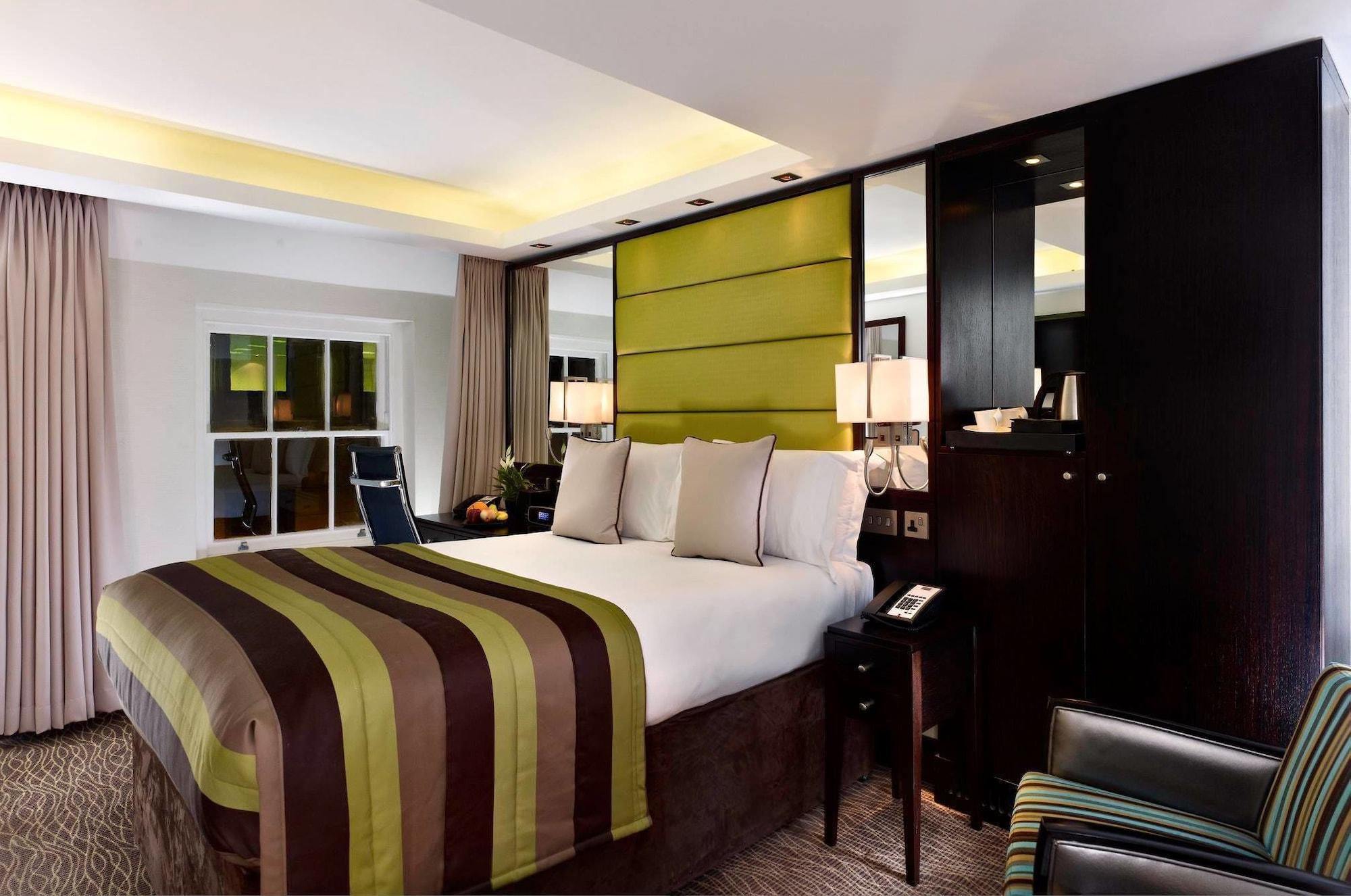 Montcalm Brewery Townhouse Hotel Лондон Екстериор снимка The photo shows a modern hotel room featuring a large bed with a striped comforter in shades of green, brown, and cream. The bed is adorned with several decorative pillows. Behind the bed, there is a contemporary headboard with a green panel design. 