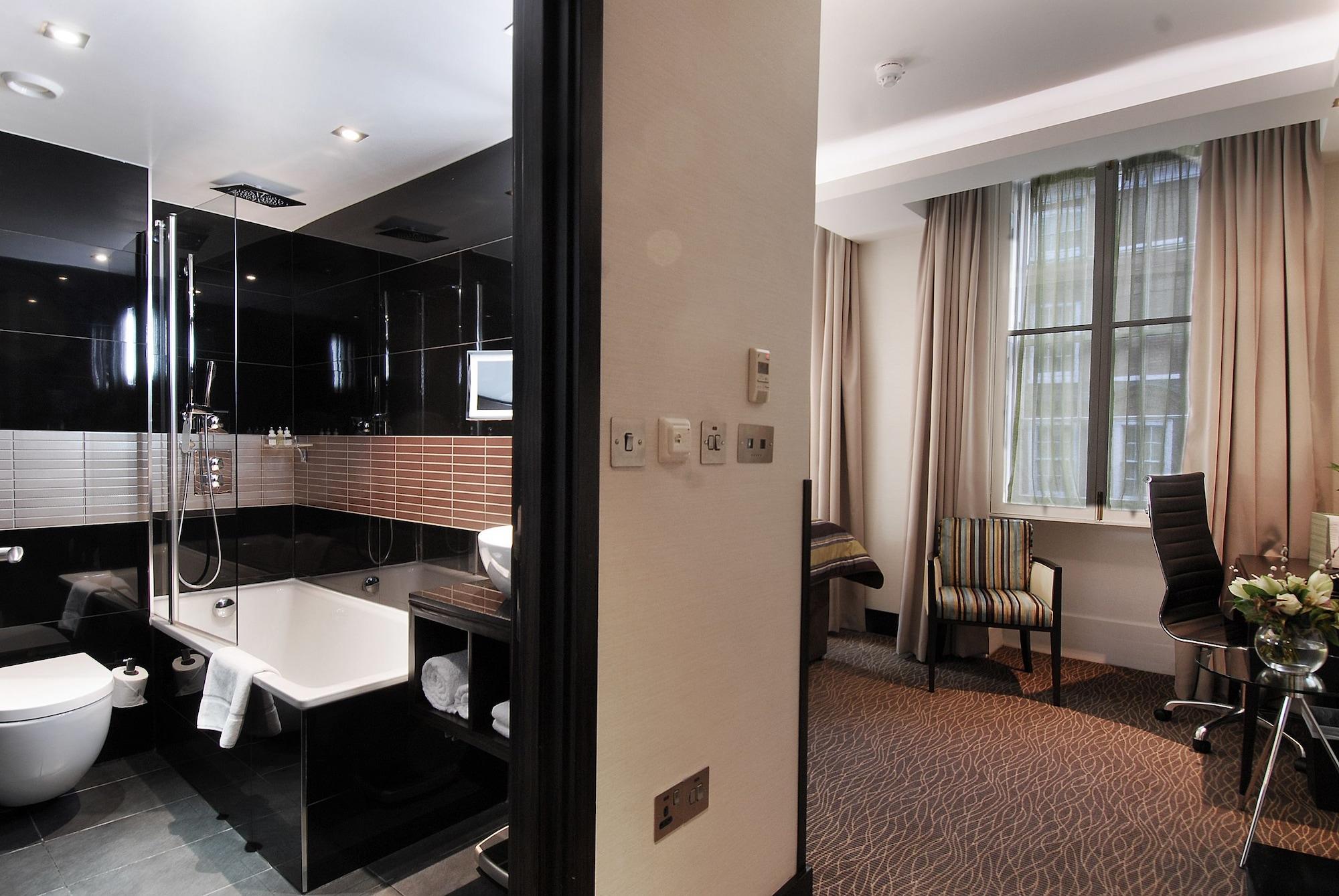 Montcalm Brewery Townhouse Hotel Лондон Екстериор снимка The photo shows a modern hotel room that features an elegant bathroom on one side and a living area on the other. 

1. **Bathroom**: The bathroom is stylishly designed with a combination of black and white tiles. It includes a bathtub, a shower area 