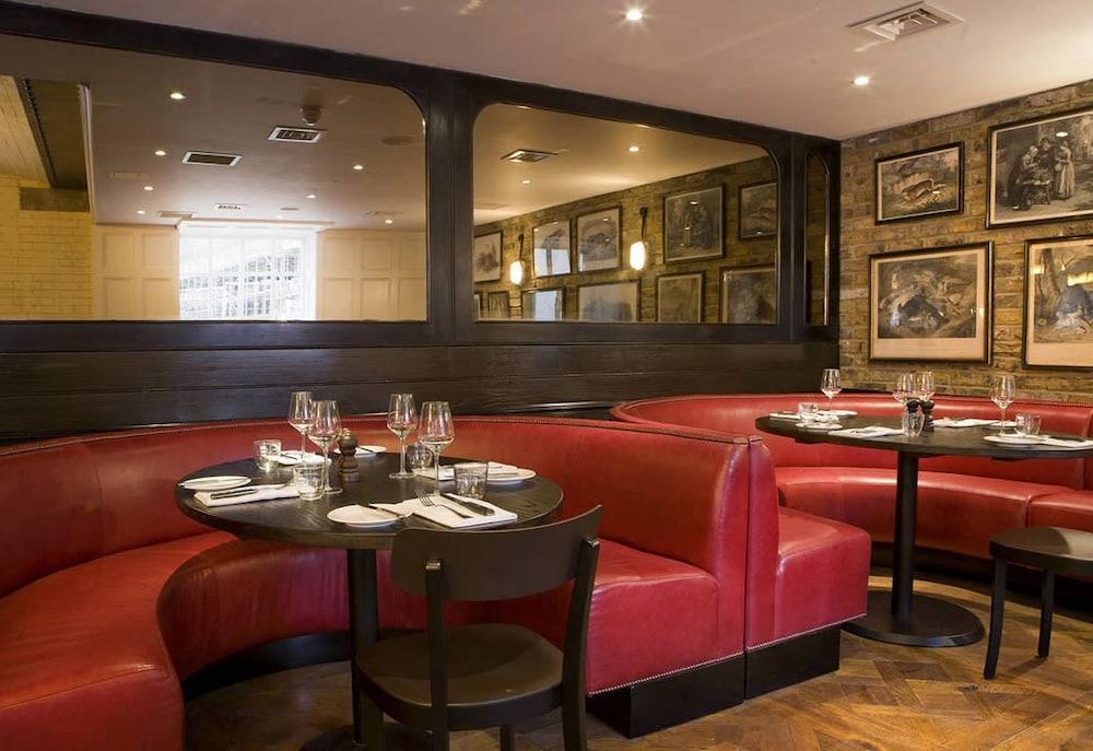 Montcalm Brewery Townhouse Hotel Лондон Екстериор снимка The image shows the interior of a restaurant featuring a warm and inviting atmosphere. There are several round tables surrounded by black chairs, with red, upholstered booths lining the walls. The decor includes framed artwork hanging on the walls, a