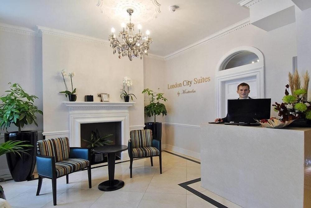 Montcalm Brewery Townhouse Hotel Лондон Екстериор снимка The photo shows the interior of a reception area in a hotel called "London City Suites." The space features a light-colored wall with the hotel's name displayed. There is a stylish chandelier hanging from the ceiling, providing warm lighting. 

In th