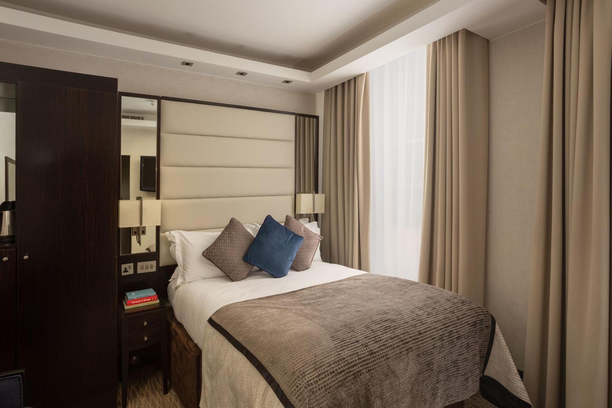 Montcalm Brewery Townhouse Hotel Лондон Екстериор снимка The photo shows a modern hotel room with a cozy design. It features a double bed with a light-colored headboard and a soft, stylish blanket. There are decorative pillows on the bed, including a blue one. On either side of the bed, there are small nig