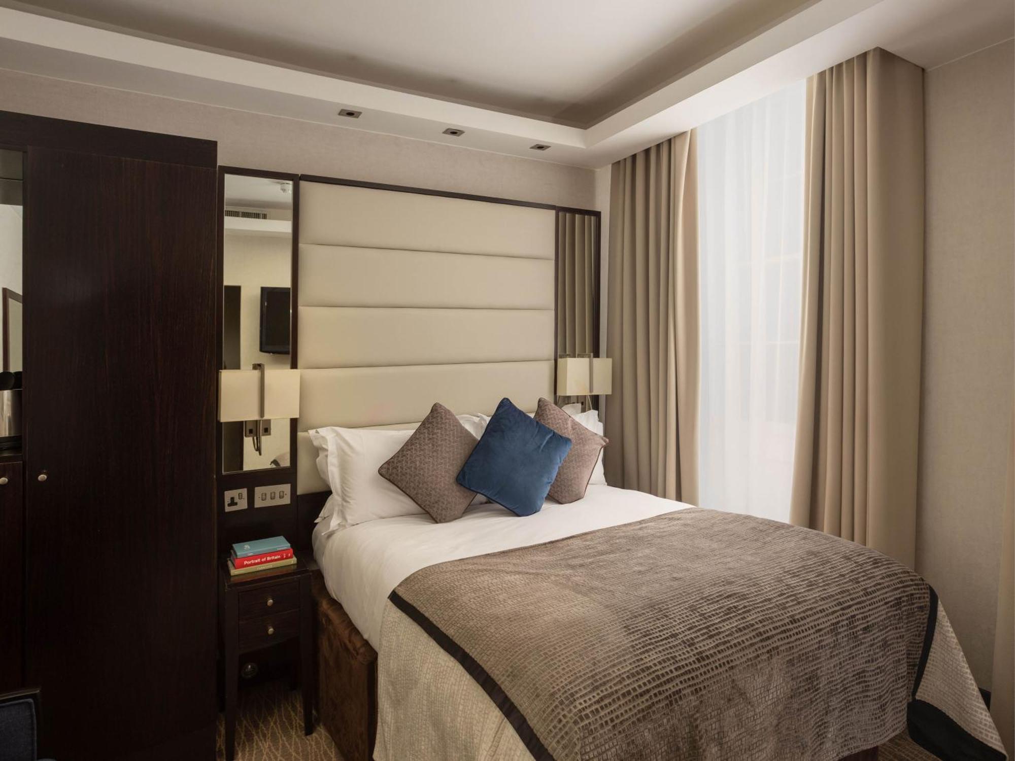 Montcalm Brewery Townhouse Hotel Лондон Екстериор снимка The image shows a cozy bedroom. It features a comfortable double bed with a light-colored duvet and decorative pillows in shades of blue and gray. The headboard is upholstered in a soft material, and there are bedside lamps on either side of the bed.