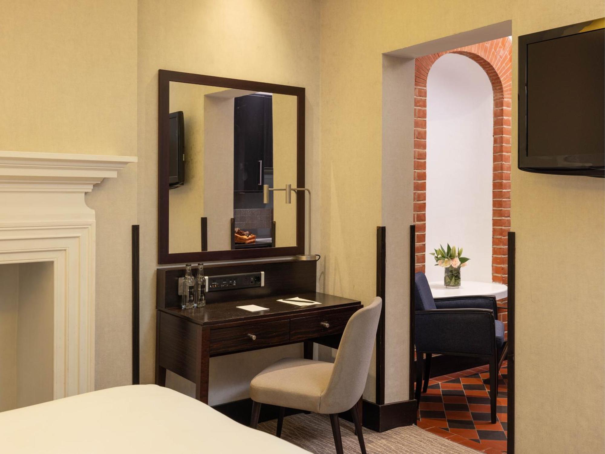 Montcalm Brewery Townhouse Hotel Лондон Екстериор снимка The photo displays a hotel room setup. On the left side, there's a bed with a simple white bedding arrangement. Adjacent to the bed, there's a wooden desk with a chair, along with a mirror above the desk. The desk area is equipped with some glassware