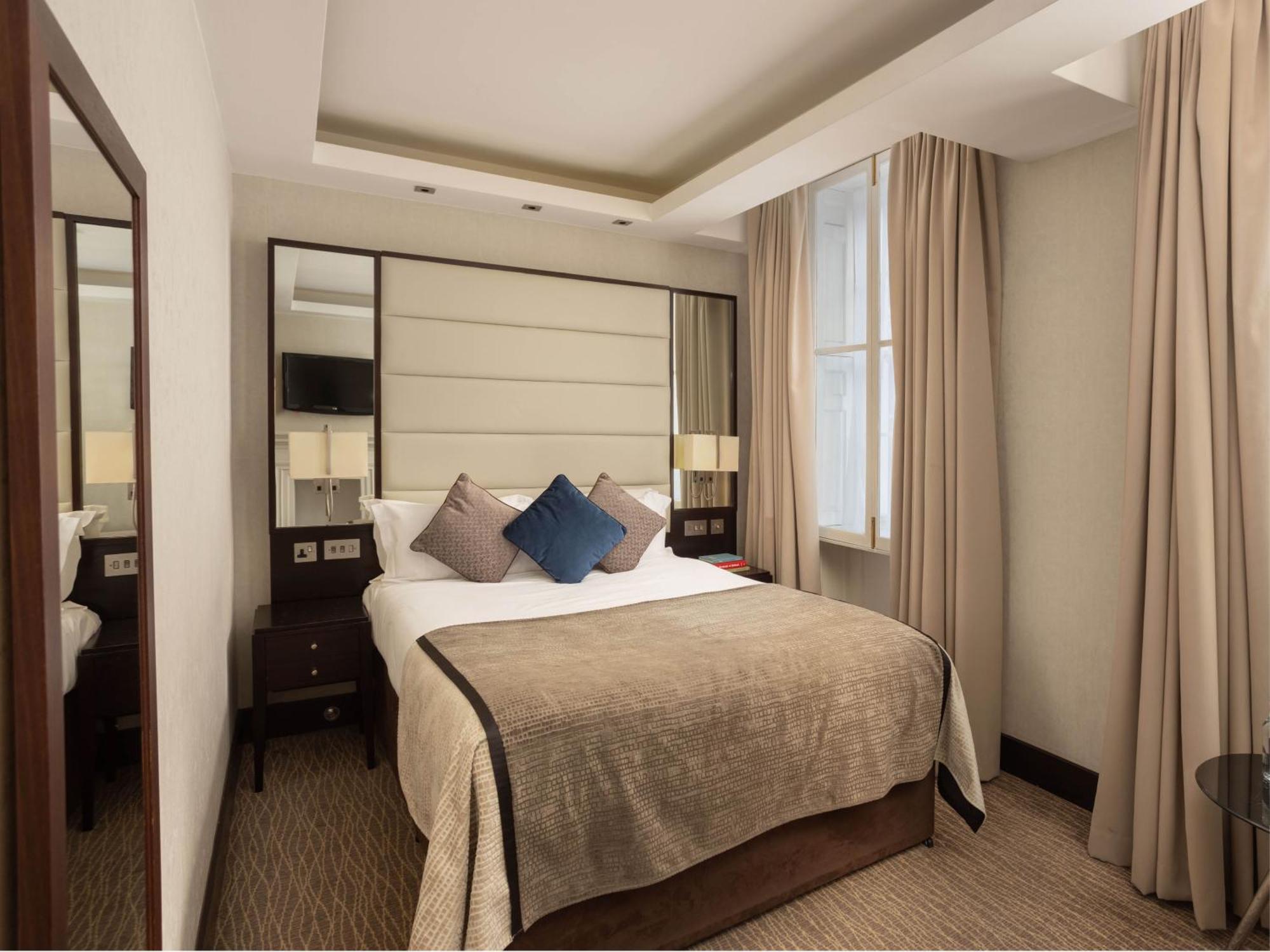 Montcalm Brewery Townhouse Hotel Лондон Екстериор снимка The photo shows a cozy hotel room with a bed as the focal point. The bed is made with neutral-colored linens and has several pillows, including a decorative blue one. There are bedside tables on either side of the bed, each with a lamp. A large mirro