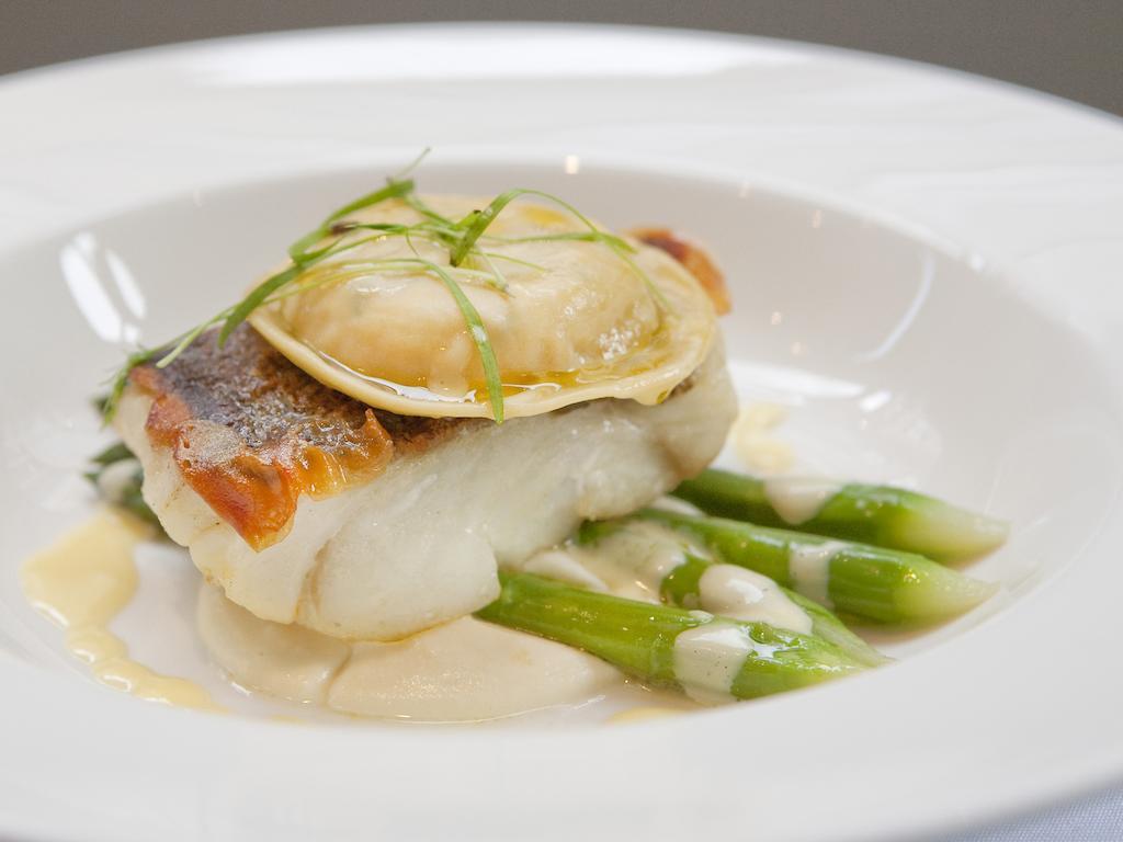 Montcalm Brewery Townhouse Hotel Лондон Екстериор снимка The image shows a beautifully presented dish featuring a piece of fish, likely a white fish, topped with a clam. It is served on a bed of green asparagus spears. The dish is garnished with thinly sliced herbs or greens, adding a touch of color. The s