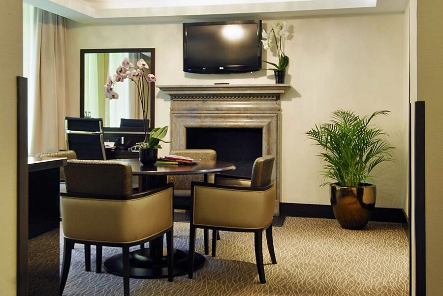 Montcalm Brewery Townhouse Hotel Лондон Екстериор снимка The photo shows a modern and stylish room with a dining or meeting area. There is a round table surrounded by four upholstered chairs. A flat-screen television is mounted on the wall above a decorative fireplace. To the side, there is a mirror reflec