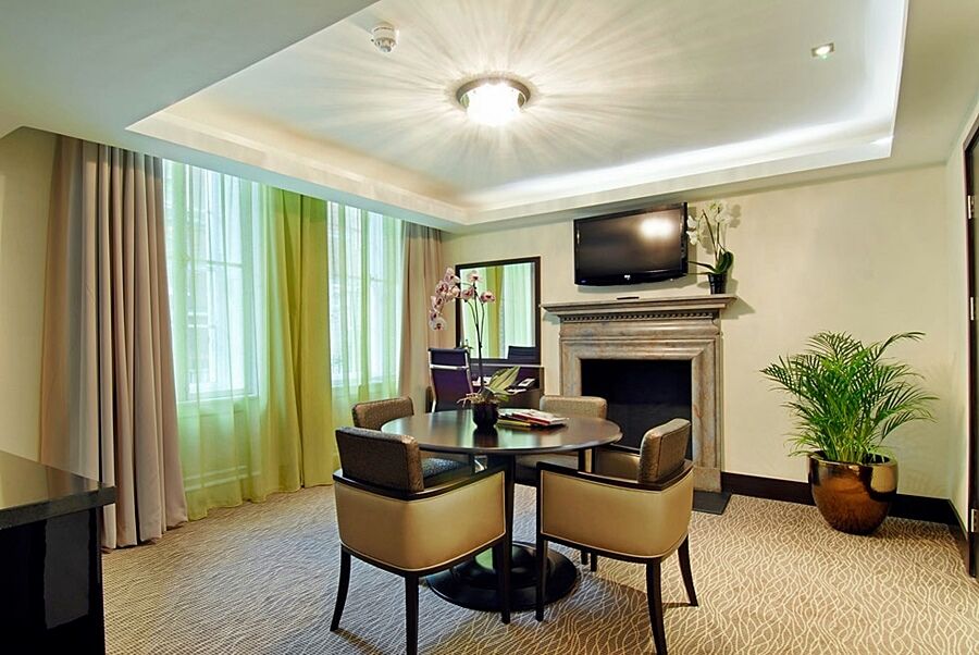 Montcalm Brewery Townhouse Hotel Лондон Екстериор снимка The photo shows a well-furnished room, likely a hotel suite or a modern living space. It features a round dining table with four comfortable chairs. The walls are adorned with light-colored decor, and there are large windows with sheer and solid curt
