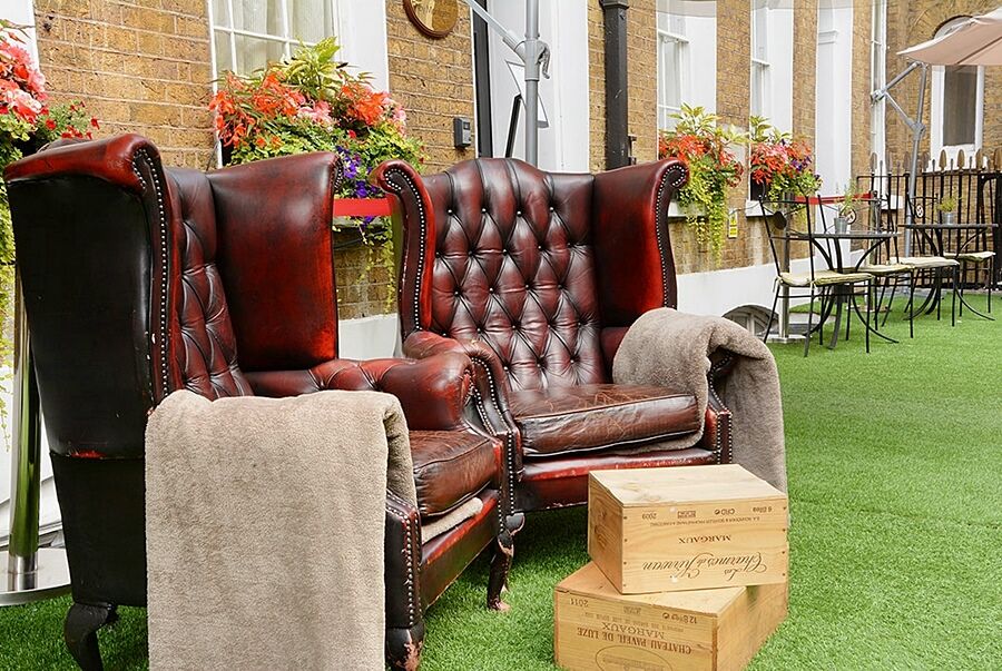 Montcalm Brewery Townhouse Hotel Лондон Екстериор снимка The photo depicts two large, elegant armchairs with a classic design, featuring rich burgundy leather upholstery and button tufting. They are positioned in a cozy outdoor setting, with lush green artificial grass beneath them. Next to the chairs, the